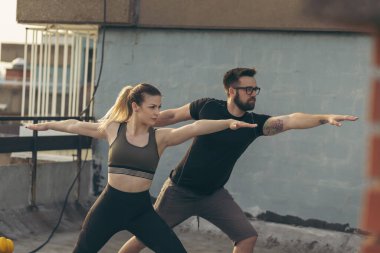 Çalışmadan önce terasta uzanan genç bir çift; arka planda kentsel ufuk çizgisi