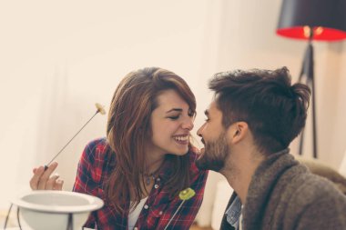 Birbirine aşık çift erimiş çikolataya meyve daldırıyor.