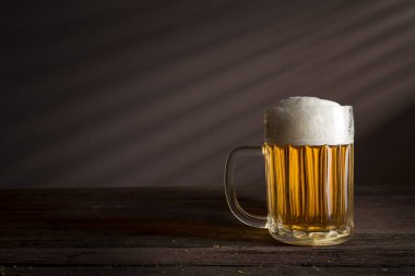 Kırsal ahşap bir masaya konmuş bir sürahi soğuk, soluk bira.