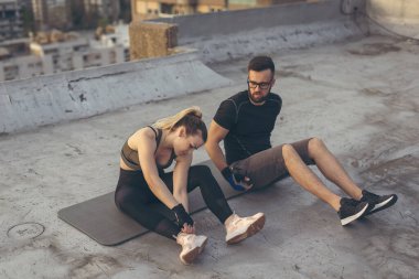 Bir çift teras için ısınıyor, yoga minderinde oturuyor, esniyor. Kadına odaklan.