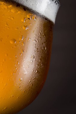 Köpüklü ıslak bir bardak soğuk light biranın ayrıntıları. Seçici odak