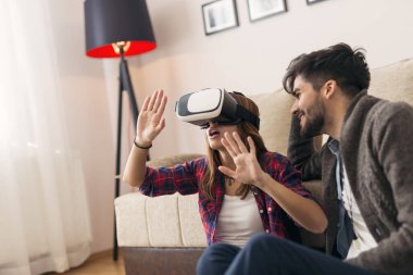 Aşık bir çift sanal gerçeklik videosu izlerken eğleniyor. Kadına odaklan.