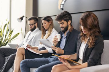 Ofis binasının bekleme odasında iş görüşmelerini bekleyen iş adamları. Sağdaki adama odaklan.