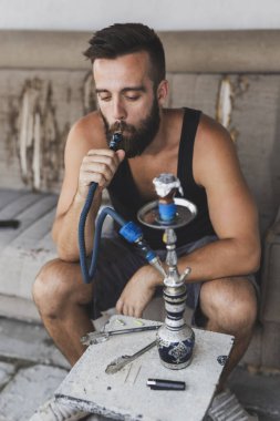 Meyve aromalı bir adam soluyor, pekmez bazlı tütün, su borusu, nargile ya da nargile kullanıyor.