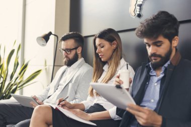 Ofis binasının bekleme odasında iş görüşmelerini bekleyen iş adamları. Kadına odaklan.