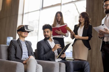 İş ekibi sanal gerçeklik simülatöründe bir müşteriye yeni bir proje sunuyor. VR gözlüklü müşteriye odaklan