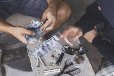 Uyuşturucu satıcısı bir uyuşturucu bağımlısına ecstasy hapı satıyor.