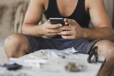 Erkek uyuşturucu satıcısının elinde akıllı bir telefon kullanma ve emir alma ayrıntıları.