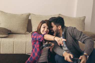 Birbirine aşık çiftler boş zamanlarının tadını çıkarıyor, oturma odasında yerde oturuyor, video oyunları oynuyor ve eğleniyorlar..