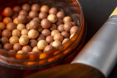 Makyaj fırçası ve barut kutusundaki yüz pudrası incileri. Kadın kozmetik ürünleri, makyaj ürünleri, bronzlaştırıcı ve kızartıcı. İncilere odaklan.