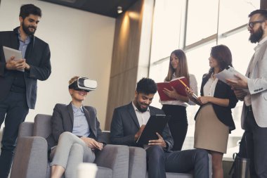 İş ekibi sanal gerçeklik simülatöründe bir müşteriye yeni bir proje sunuyor. VR gözlük takan kadına odaklan.