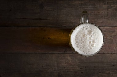 Kırsal bir ahşap masaya yerleştirilmiş soğuk soluk biranın üst görüntüsü.