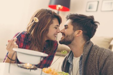 Birbirine aşık bir çift erimiş çikolataya meyve daldırıyor. Kıza odaklan.