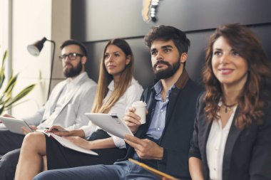 Modern bir konferans odasında toplantı yapan dört iş adamı. Sağdaki adama odaklan.