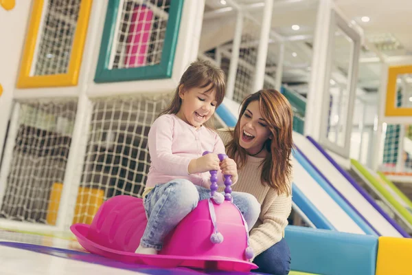妈妈和女儿在一个五彩缤纷的游戏室里玩耍 女儿在玩巨大的粉色毛毛毛虫秋千时玩得很开心 专注于女儿 — 图库照片
