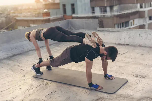 夫妻二人在楼顶的平台上锻炼 做直臂跳板练习 把注意力放在那家伙身上 — 图库照片