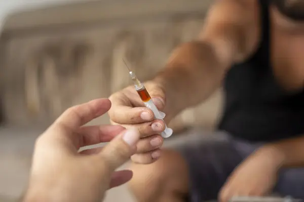 ヘロインシリンジを共有する2人の静脈内麻薬使用者の手の詳細 ヘロインで撮影ジャンキー シリンジとそれを保持する指に選択的な焦点 — ストック写真