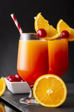 İki soğuk tekila gündoğumu kokteyli, tekila, nar suyu ve portakal suyu ile süslenmiş portakal suyu ve maraska kirazı.