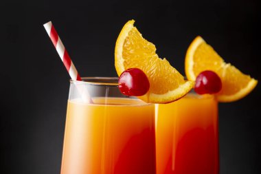 İki soğuk tekila kokteyli, tekila, nar suyu ve portakal suyu ile süslenmiş portakal suyu ve maraska kirazı. Camdaki kiraza odaklan.