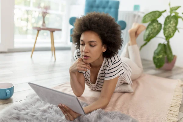 stock image Female blogger lying on the living room floor, writing a new blog post, working remotely from home