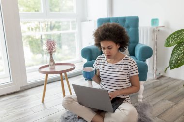 Kadın covid-19 salgını sırasında evden işe gidip geliyor, dizüstü bilgisayarda çalışıyor ve kahve içiyor, kadın uzaktan evden çalışıyor.