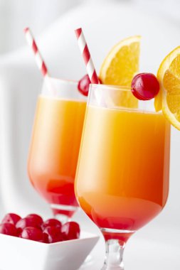İki soğuk tekila kokteyli, tekila, nar suyu ve portakal suyu ile süslenmiş portakal suyu ve maraska kirazı. Camdaki kiraza odaklan.