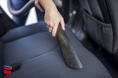 Kadın elinin elinde elektrikli süpürge ve elektrikli süpürge tutması ve araba koltukları ve iç mekan.