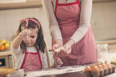 Anne ve kızının kurabiye pişirmesi, mutfak tezgahında unla oynaması.