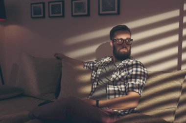 Kanepede oturan yakışıklı genç adam, evde dinleniyor.