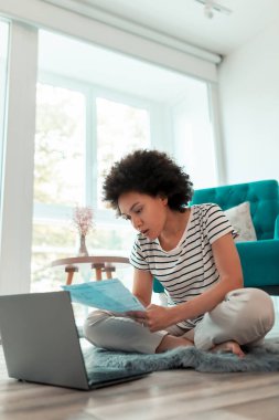 Güzel bir kadın oturma odasında oturuyor, banka kredi ödeme oranlarını hesaplıyor ve ev faturalarını ödüyor.