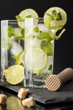 Beyaz rom, limon suyu ve limon dilimleri ve nane yapraklarıyla süslenmiş bir bardak soğuk mojito kokteyli.
