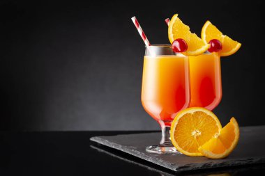 İki soğuk tekila gündoğumu kokteyli, tekila, nar suyu ve portakal suyu ile süslenmiş portakal suyu ve maraska kirazı.