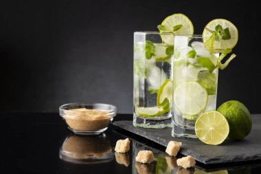 Beyaz rom, limon suyu ve limon dilimleri ve nane yapraklarıyla süslenmiş bir bardak soğuk mojito kokteyli. Daha yakın cama odaklan.