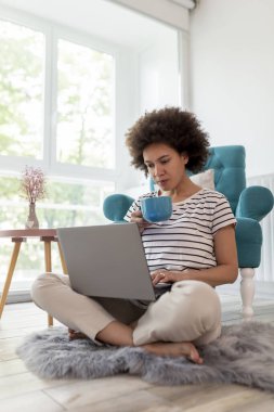 Coronavirus salgını sırasında evde çalışan, dizüstü bilgisayar kullanan ve kahve içen bir kadın, evden uzaktan çalışan bir kadın.