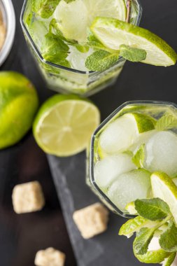 Beyaz rom, limon suyu ve limon dilimleri ve nane yapraklarıyla süslenmiş tonik ile birlikte bir bardak soğuk mojito. Nane yapraklarına odaklan