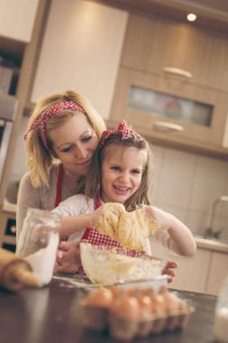 Mutfakta annesiyle hamur yoğurup eğlenen güzel bir kız. 
