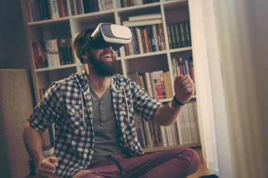 Genç adam boş zamanlarında sanal gerçeklik gözlüğü takıp, bir video oyunu oynuyor.