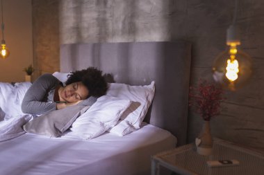 Sabahları pijama giyen, evde dinlenen ve uyuyan genç ve güzel bir ırk kadını.