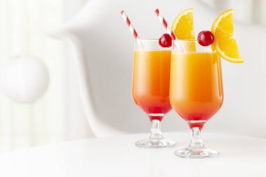 İki soğuk tekila kokteyli, tekila, nar suyu ve portakal suyu ile süslenmiş portakal suyu ve maraska kirazı. Camdaki kiraza odaklan.