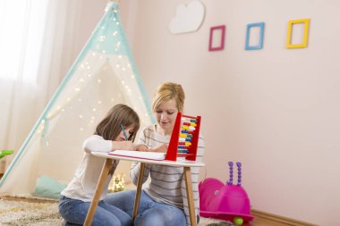 Anne ve kızı, abaküs ile matematik öğreniyor, özet çıkarmayı ve çıkarmayı öğreniyor. Kızına odaklan.