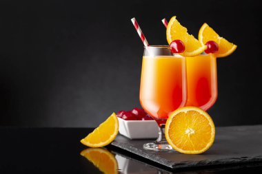 İki soğuk tekila gündoğumu kokteyli, tekila, nar suyu ve portakal suyu ile süslenmiş portakal suyu ve maraska kirazı.