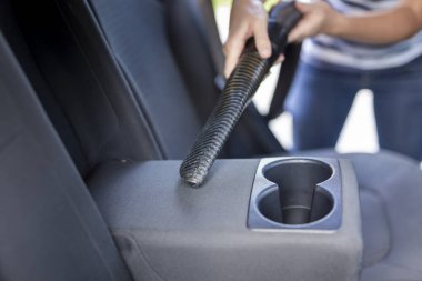 Kadın elinin elinde elektrikli süpürge ve elektrikli süpürge tutması ve araba koltukları ve iç mekan.