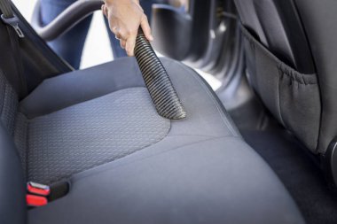 Kadın elinin elinde elektrikli süpürge ve elektrikli süpürge tutması ve araba koltukları ve iç mekan.