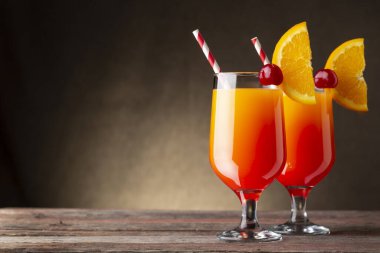 İki soğuk tekila gündoğumu kokteyli, tekila, nar suyu ve portakal suyu ile süslenmiş portakal suyu ve maraska kirazı.