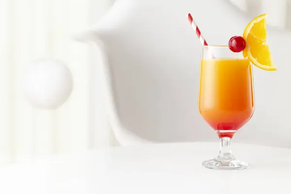 Cold tequila sunrise cocktail with tequila, pomegranate juice and orange juice decorated with slices of orange and maraschino cherries. Focus on the cherry on the glass