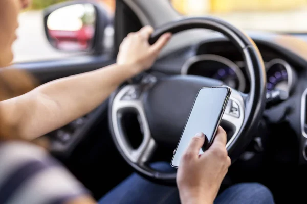 ステアリングホイールを保持し 車を運転しながらスマートフォンにテキストメッセージを入力する女性の手の詳細 — ストック写真