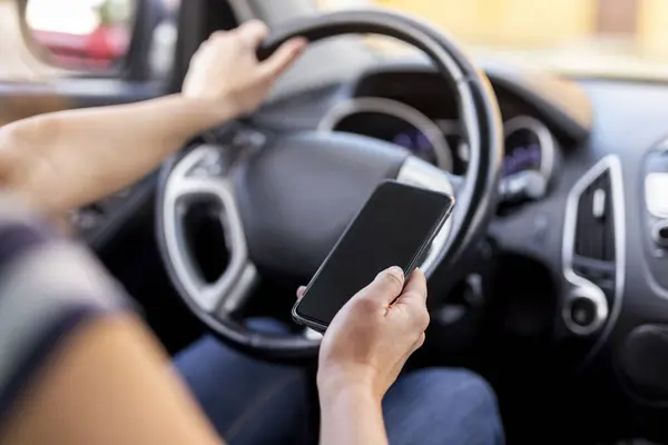ステアリングホイールを保持し 車を運転しながらスマートフォンにテキストメッセージを入力する女性の手の詳細 — ストック写真