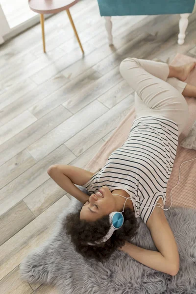 바닥에 헤드셋을 음악을 집에서 휴식을 레이스 여자의 — 스톡 사진