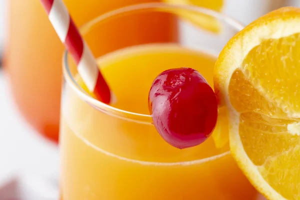オレンジとマラシノのチェリーのスライスで装飾されたテキーラ ザクロジュース オレンジジュースとオレンジジュースの2つの冷たいテキーラ日の日の出カクテルの高角度ビュー グラスのチェリーに焦点を当てる — ストック写真