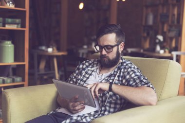 Yakışıklı genç hippi bir kafede dalgın dalgın oturuyor, sabah kahvesini içiyor, elinde bir tablet bilgisayar tutuyor ve internete yüklüyor.